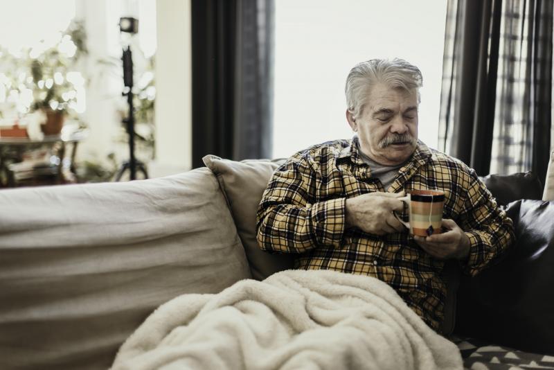 Man in heated blanket with mug