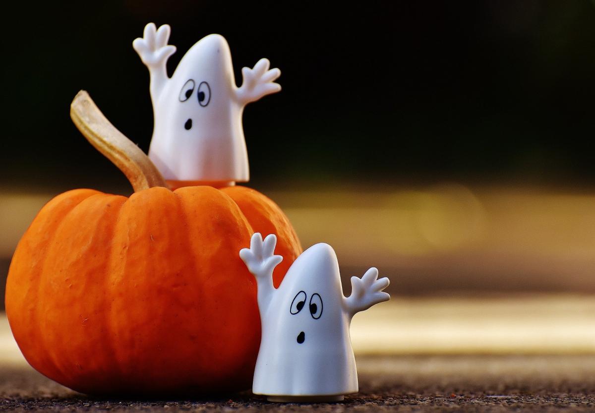 Two ghost figurines near a small pumpkin