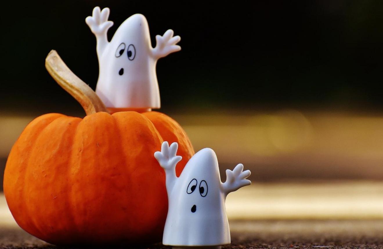 Two ghost figurines near a small pumpkin